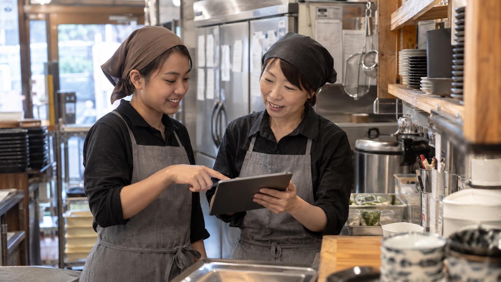 日本の飲食店でスタッフがタブレットを見ながら業務を確認するイメージ